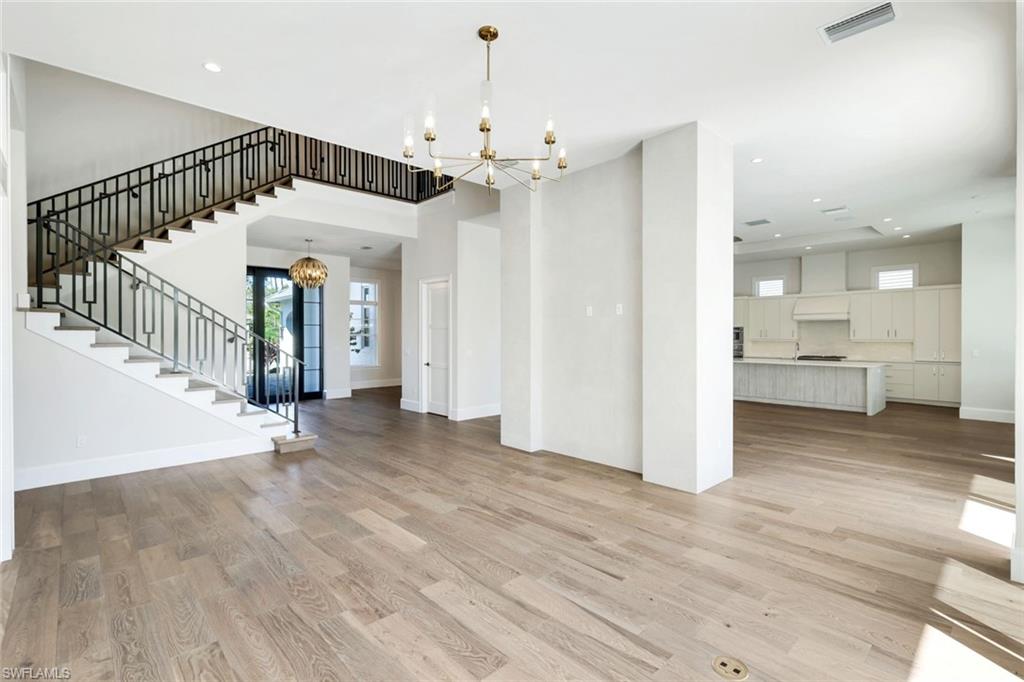 16716 Enclave Circle Naples, FL 34110 - Photo 20 of 50 Unfurnished living room with suspended lighting and light wood-type flooring