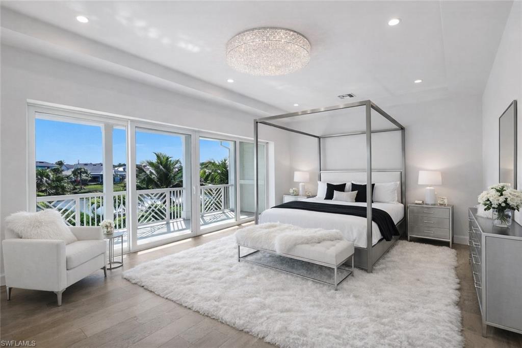 16716 Enclave Circle Naples, FL 34110 - Photo 26 of 50 Bedroom with access to exterior, light wood-style flooring, and hanging lights