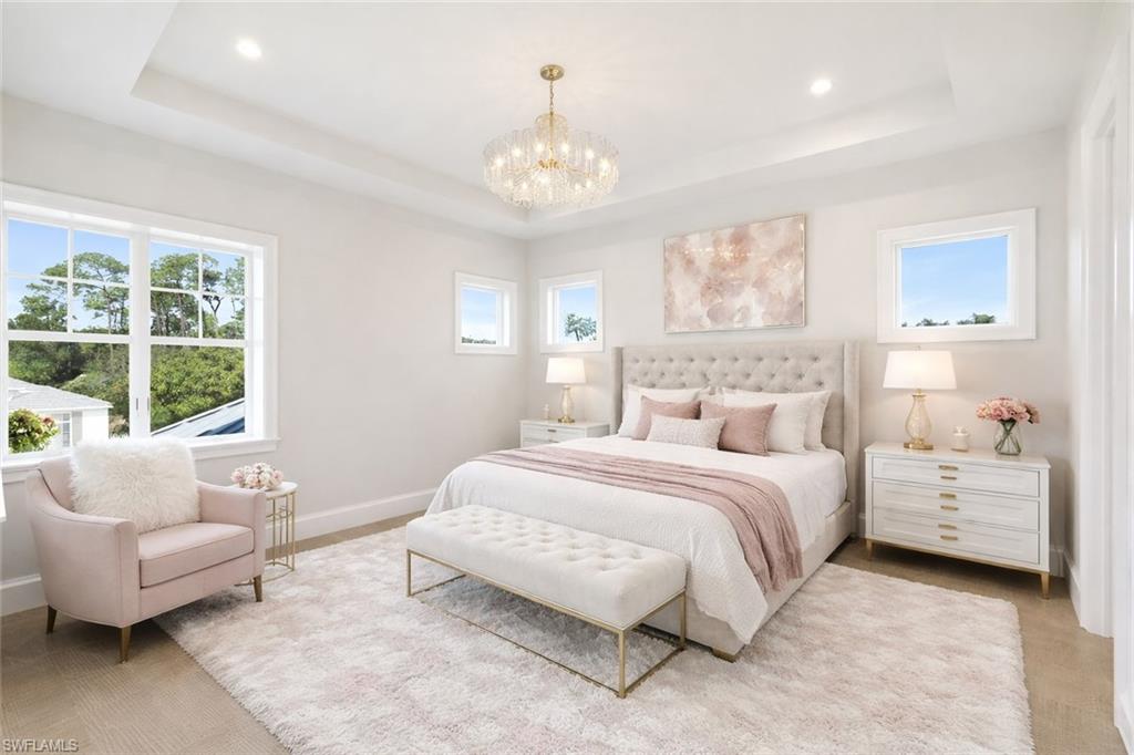 16716 Enclave Circle Naples, FL 34110 - Photo 38 of 50 Bedroom with multiple windows, a chandelier, and a tray ceiling