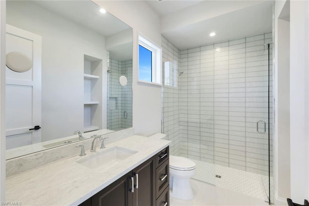 16716 Enclave Circle Naples, FL 34110 - Photo 39 of 50 Bathroom featuring a shower stall, vanity, built in shelves, and recessed lighting