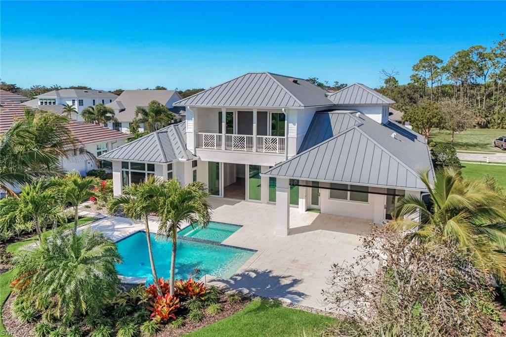 16716 Enclave Circle Naples, FL 34110 - Photo 5 of 50 Back of house with a standing seam roof, a patio area, a balcony, an outdoor pool, and stucco siding