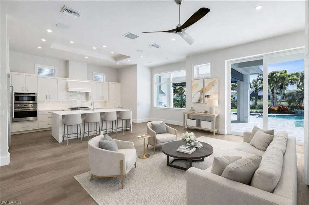16716 Enclave Circle Naples, FL 34110 - Photo 8 of 50 Living room featuring ceiling fan, light wood-type flooring, healthy amount of natural light, recessed lighting, and a raised ceiling