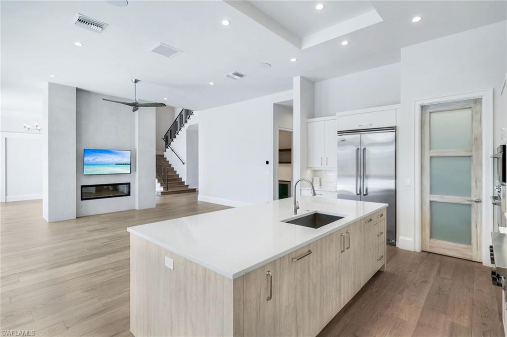 16716 Enclave Circle Naples, FL 34110 - Photo 10 of 50 Kitchen with a kitchen island with sink, light wood finished floors, stainless steel built in refrigerator, light wood finish cabinetry, and recessed lighting