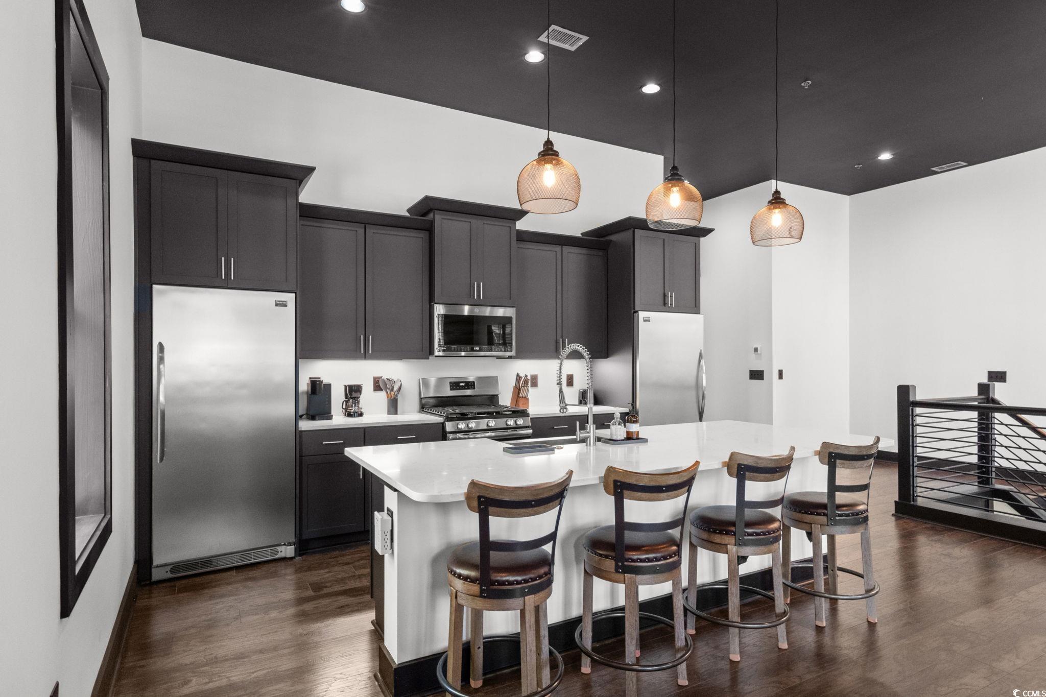 34 Shady Moss Loop, Unit 34 Murrells Inlet, SC 29576 - Photo 8 of 40 Kitchen with appliances with stainless steel finishes, hanging light fixtures, a breakfast bar, dark wood-style flooring, and a kitchen island with sink