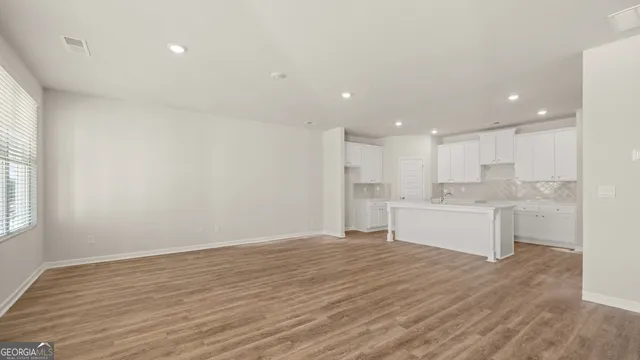a large white kitchen with kitchen island a sink wooden floor and white cabinets