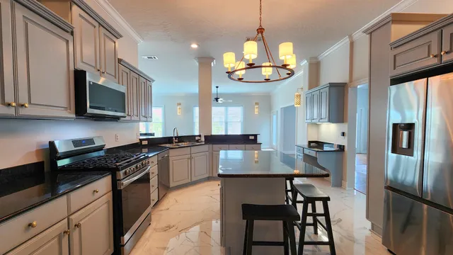 a kitchen with stainless steel appliances granite countertop a stove a refrigerator a sink a stove and chairs with wooden floor