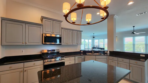 a kitchen with stainless steel appliances granite countertop a sink a stove and a microwave oven with white cabinets