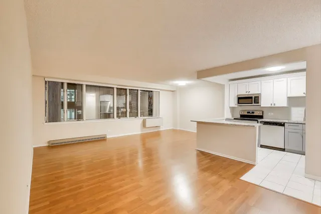 a large white kitchen with kitchen island a sink wooden floor and a refrigerator