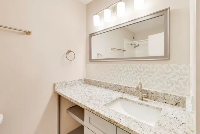 a bathroom with a granite countertop sink and a mirror