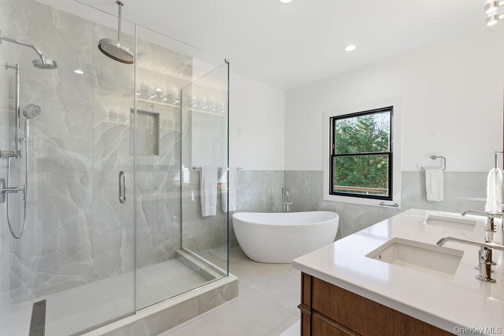 768 Bridgehampton Sag Harbor Bridgehampton, NY 11932 - Photo 18 of 35 Full bathroom with a freestanding tub, double vanity, tile walls, a marble finish shower, and wainscoting