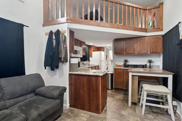 a living room with stainless steel appliances kitchen island a table and a couch