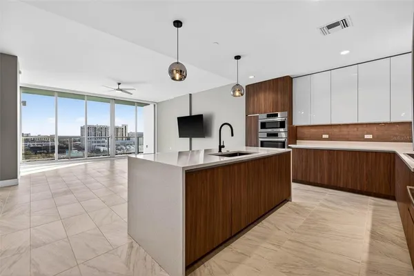 a large kitchen with a large counter top a sink a window and stainless steel appliances