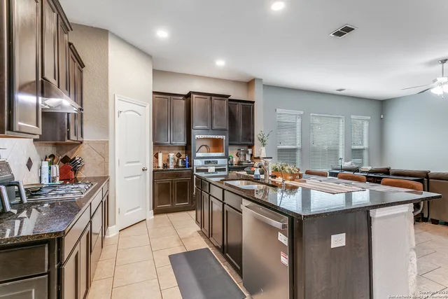a kitchen with kitchen island stainless steel appliances a sink stove top oven and refrigerator