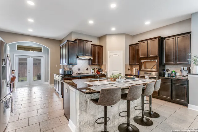 a kitchen with stainless steel appliances a stove a sink a oven a dining table and chairs