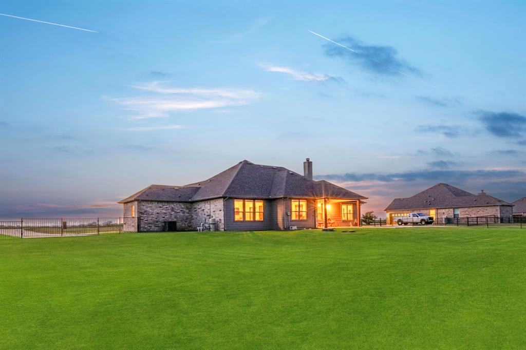 634 Gant Road Sherman, TX 75090 - Photo 40 of 40 Expansive green lawn with a stone and stucco residence featuring a covered patio, multiple windows, and a fenced perimeter