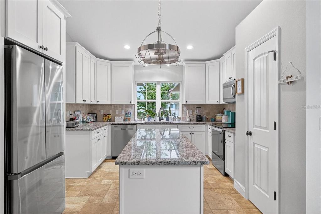 8160 Southeast 164th Place Summerfield, FL 34491 - Photo 14 of 56 a kitchen with stainless steel appliances granite countertop a refrigerator a sink dishwasher a stove and white cabinets with wooden floor