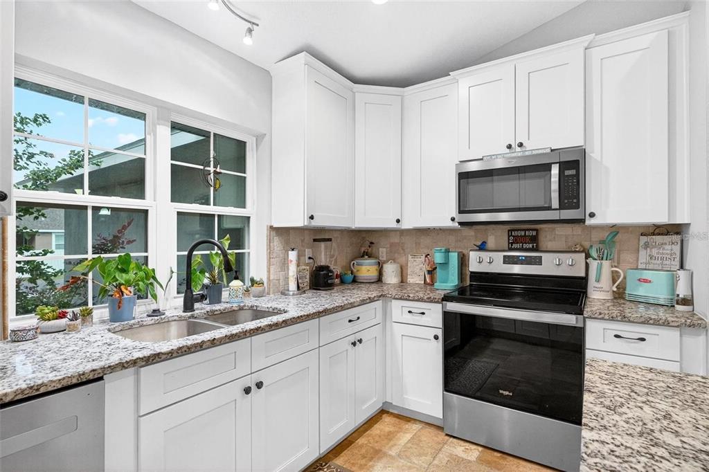 8160 Southeast 164th Place Summerfield, FL 34491 - Photo 17 of 56 a kitchen with granite countertop a stove a sink and a microwave