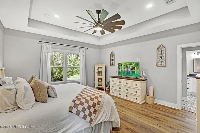 a bedroom with a bed and a dresser with wooden floor