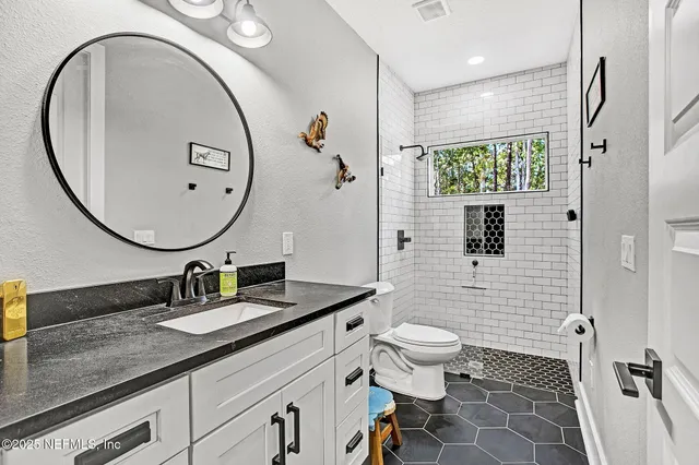 a bathroom with a granite countertop sink mirror vanity and toilet