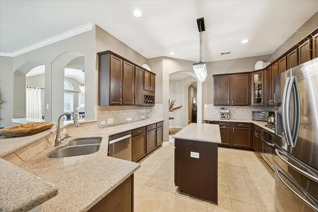 a large kitchen with stainless steel appliances kitchen island granite countertop a sink stove and refrigerator