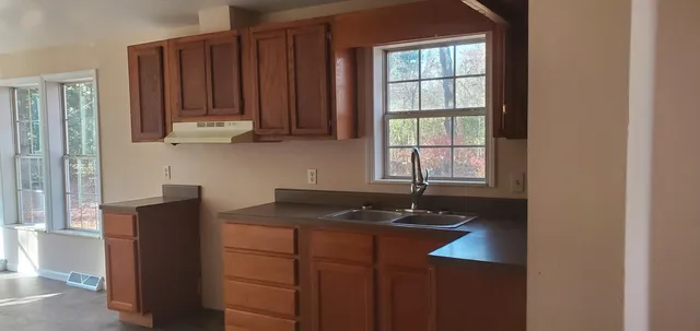 a kitchen with granite countertop a sink window and cabinets