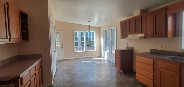a view of kitchen with wooden floor and cabinets