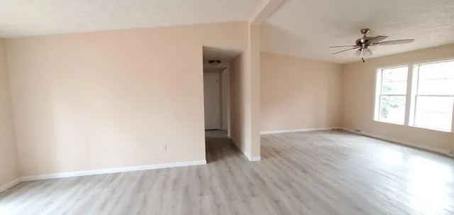 an empty room with wooden floor closet and windows