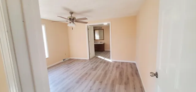 a view of a livingroom with wooden floor and a ceiling fan