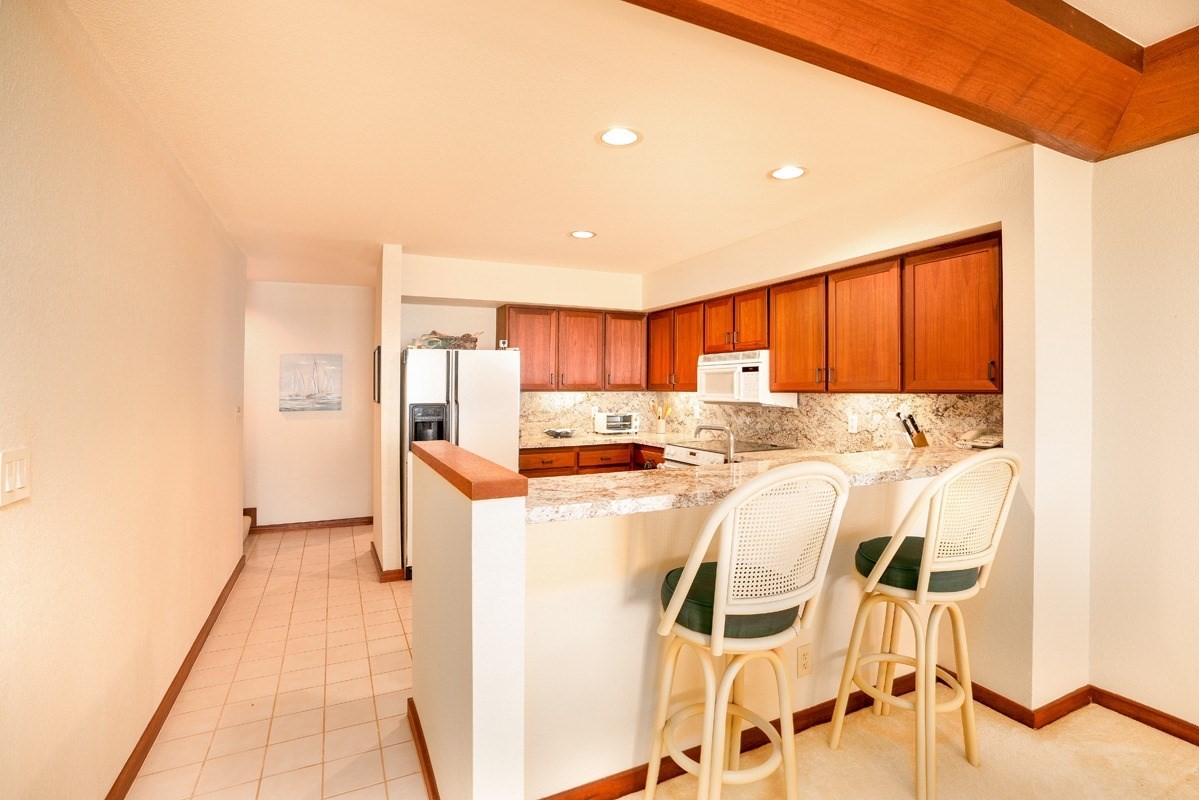 2221 Kapili Road, Unit 52 Koloa, HI 96756 - Photo 6 of 26 a kitchen with granite countertop cabinets and refrigerator
