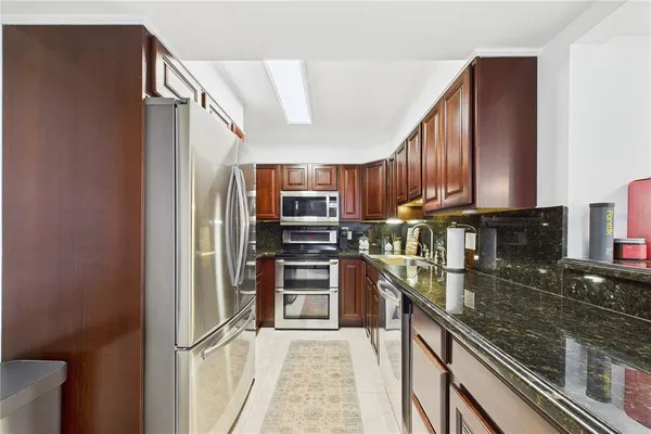a kitchen with stainless steel appliances granite countertop a refrigerator and a sink