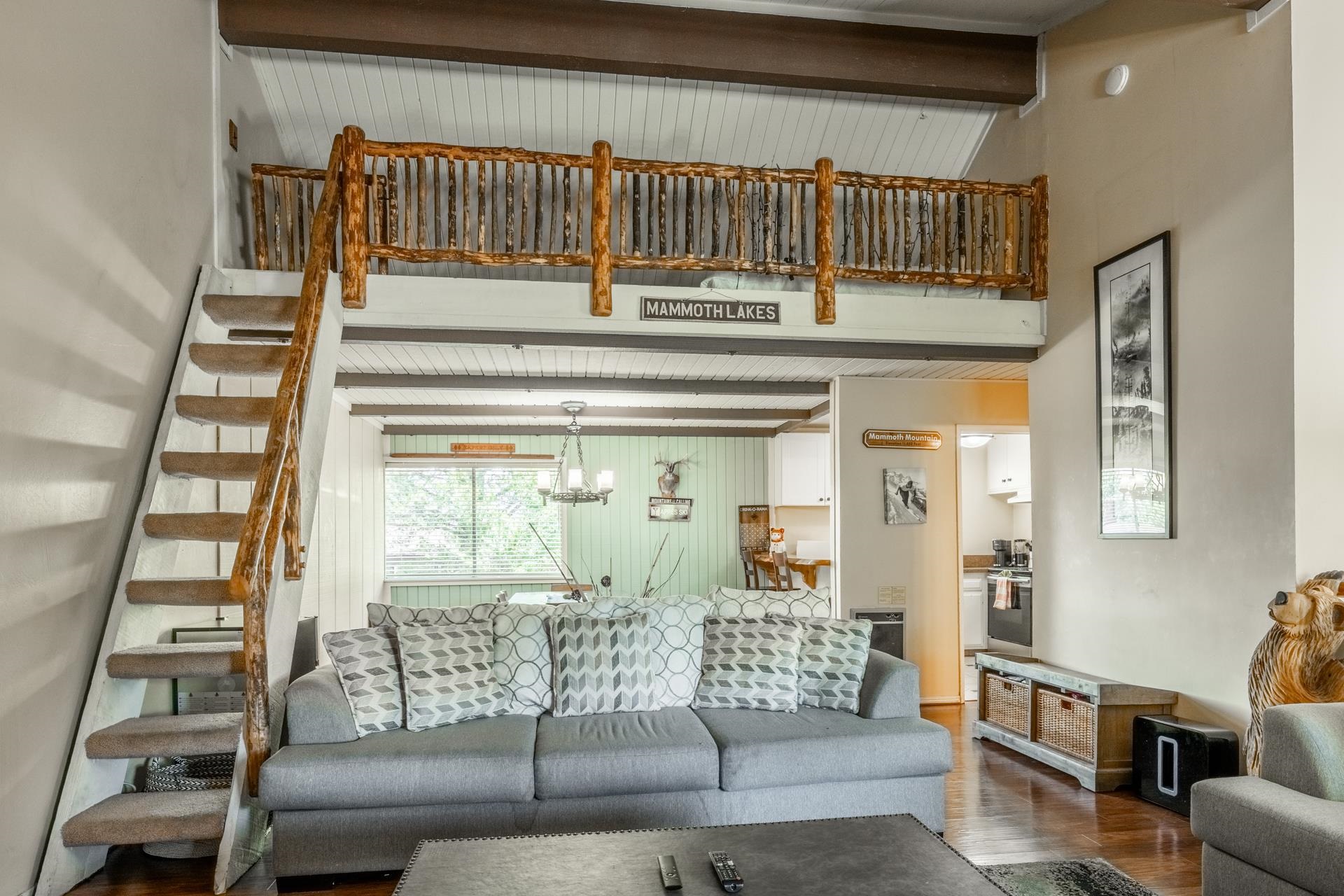 165 Old Mammoth Road, Unit 3 Mammoth Lakes, CA 93546 - Photo 6 of 48 Interior living space featuring a loft with a log railing, a staircase with a log handrail and carpeted treads, wood-finish flooring, and exposed ceiling beams