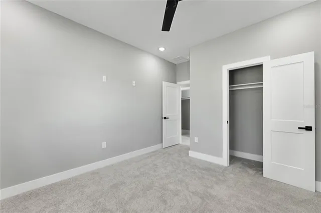 a view of an empty room and chandelier fan