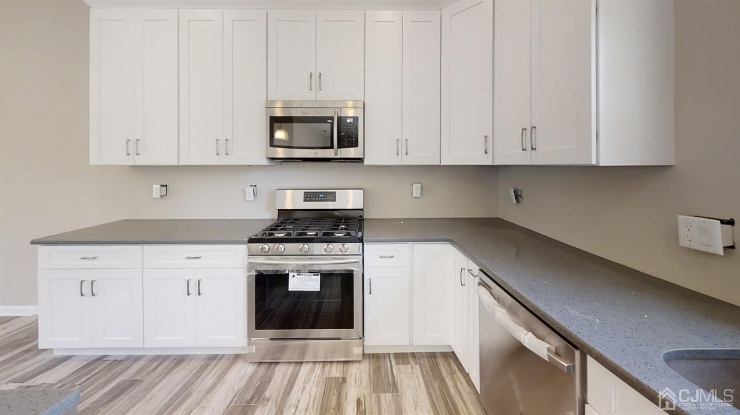 16 Idlewild Road Edison, NJ 08817 - Photo 4 of 15 a kitchen with stainless steel appliances granite countertop a stove a white cabinet and a granite countertops with wooden floor