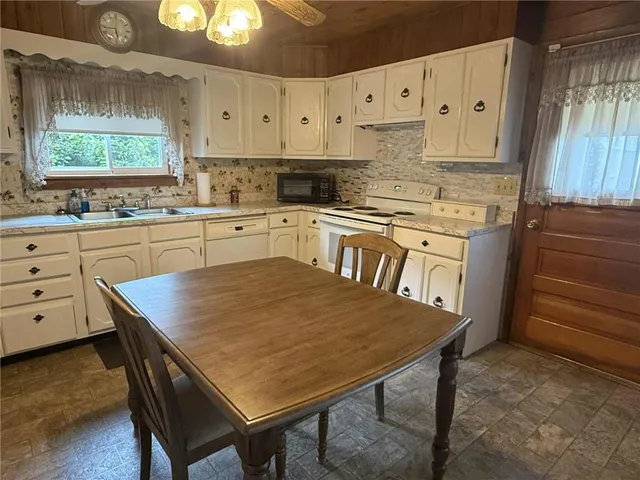 a kitchen with stainless steel appliances granite countertop a table chairs sink and cabinets
