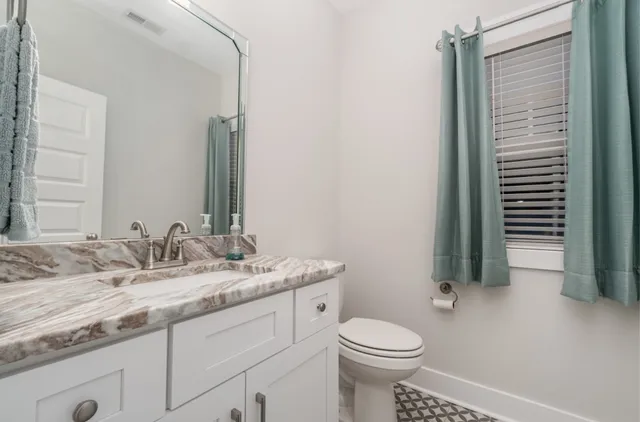 a bathroom with a granite countertop sink toilet and mirror