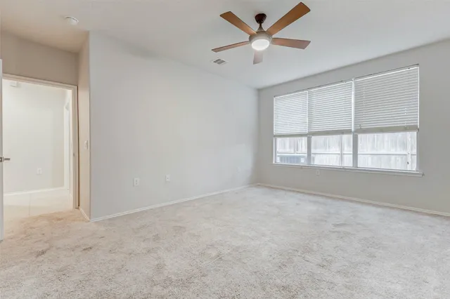 an empty room with a window and a ceiling fan