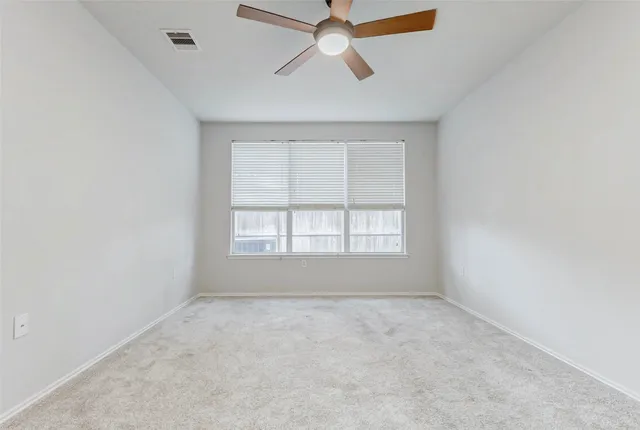 an empty room with ceiling fan and window
