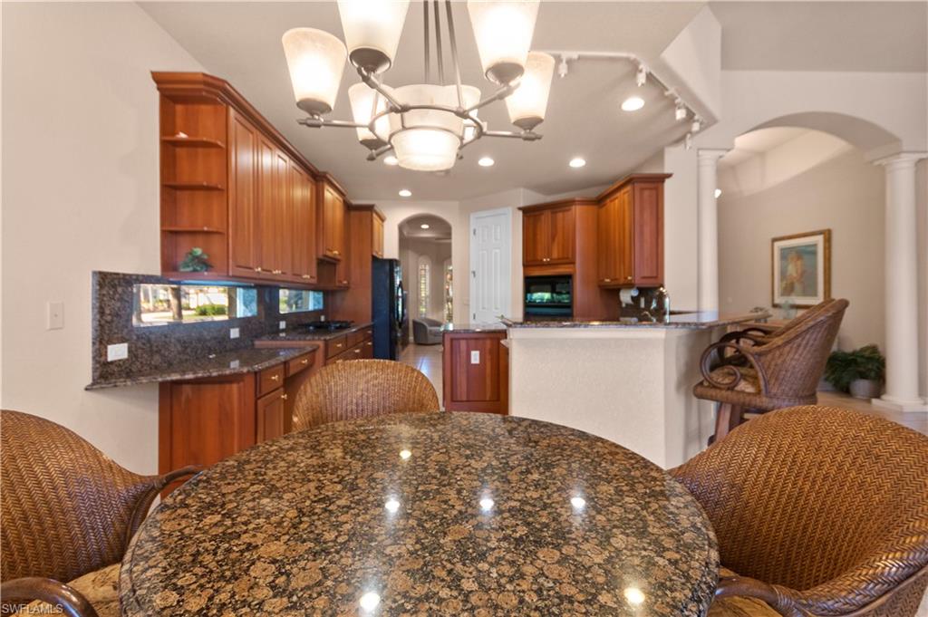 8855 Largo Mar Drive Estero, FL 33967 - Photo 12 of 50 a kitchen with stainless steel appliances kitchen island granite countertop a refrigerator a sink a stove and a wooden cabinets
