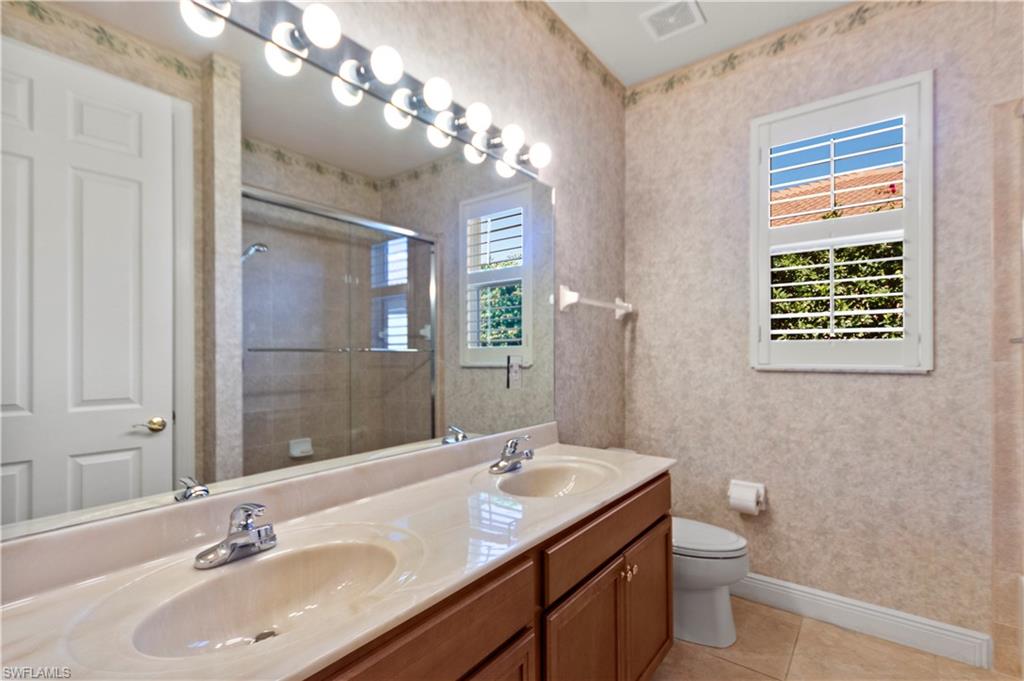 8855 Largo Mar Drive Estero, FL 33967 - Photo 29 of 50 a bathroom with a granite countertop sink a toilet a mirror a vanity and shower