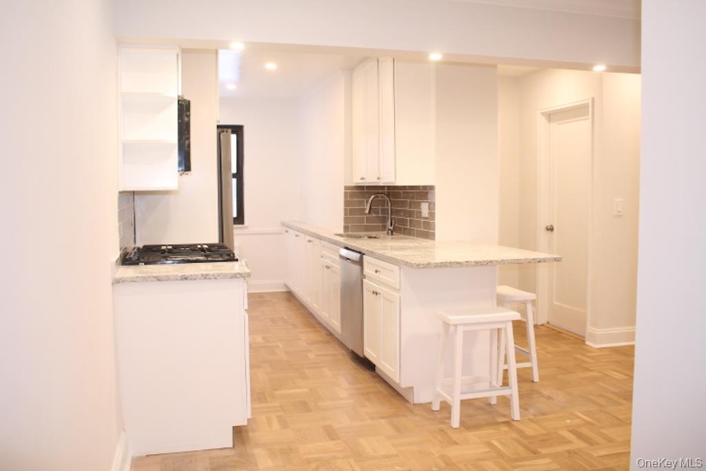 50 White Oak Street, Unit 1C New Rochelle, NY 10801 - Photo 5 of 24 a kitchen with stainless steel appliances kitchen island granite countertop a stove a sink and white cabinets