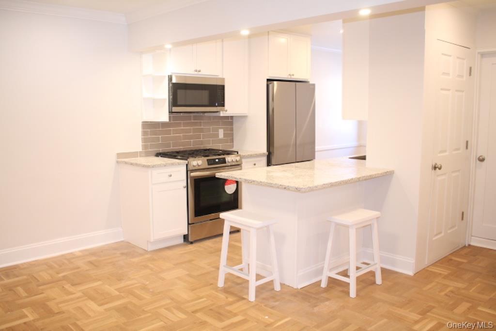 50 White Oak Street, Unit 1C New Rochelle, NY 10801 - Photo 6 of 24 a kitchen with stainless steel appliances granite countertop a stove top oven microwave and refrigerator