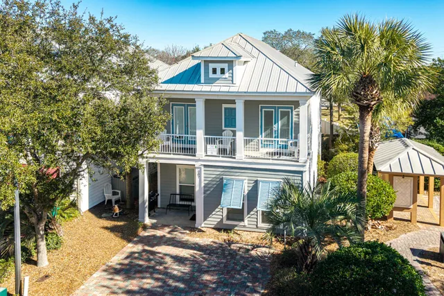 a view of a white house with large windows and a small yard
