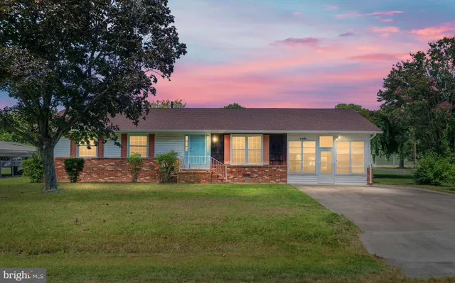 a front view of a house with a garden and trees