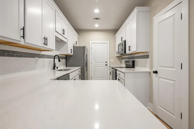 a large white kitchen with stainless steel appliances