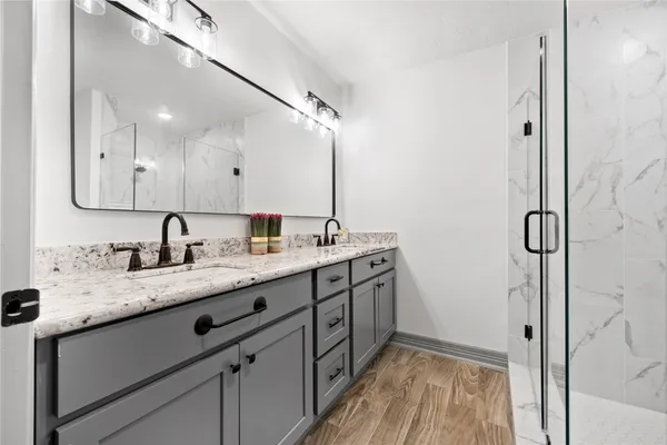 a bathroom with a granite countertop sink a mirror and shower