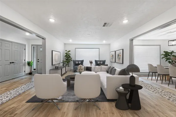 a living room with couches and a dining table with wooden floor