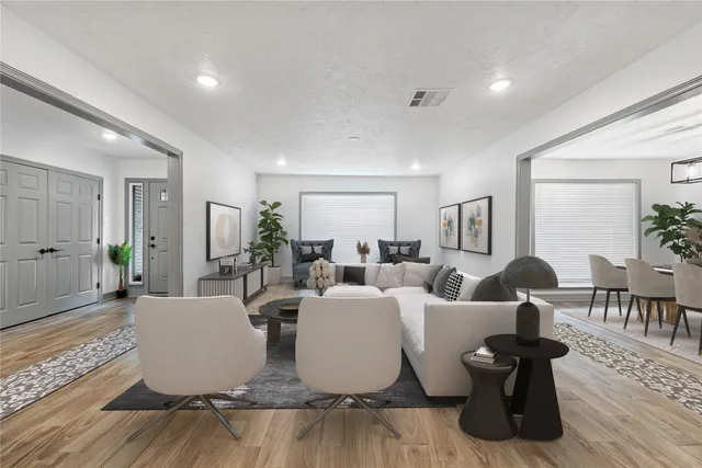 a living room with couches and a dining table with wooden floor