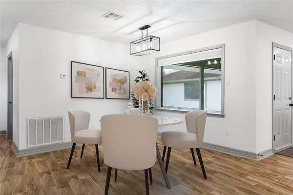 a dining room with wooden floor a chandelier a wooden table and chairs