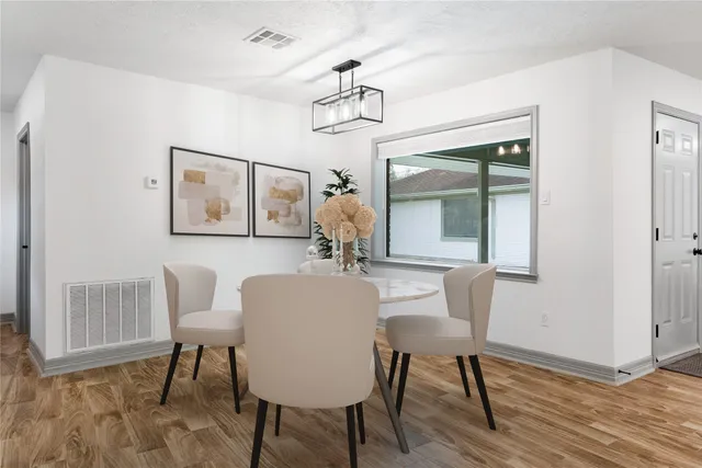 a dining room with wooden floor a chandelier a wooden table and chairs