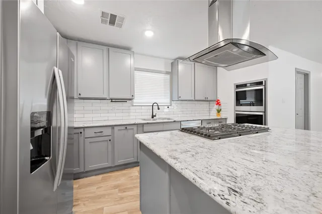 a kitchen with stainless steel appliances granite countertop a sink refrigerator and cabinets